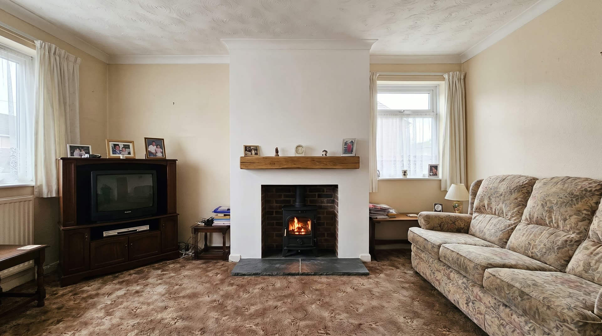 After — the same room with a slate hearth, oak beam and a lit log burner